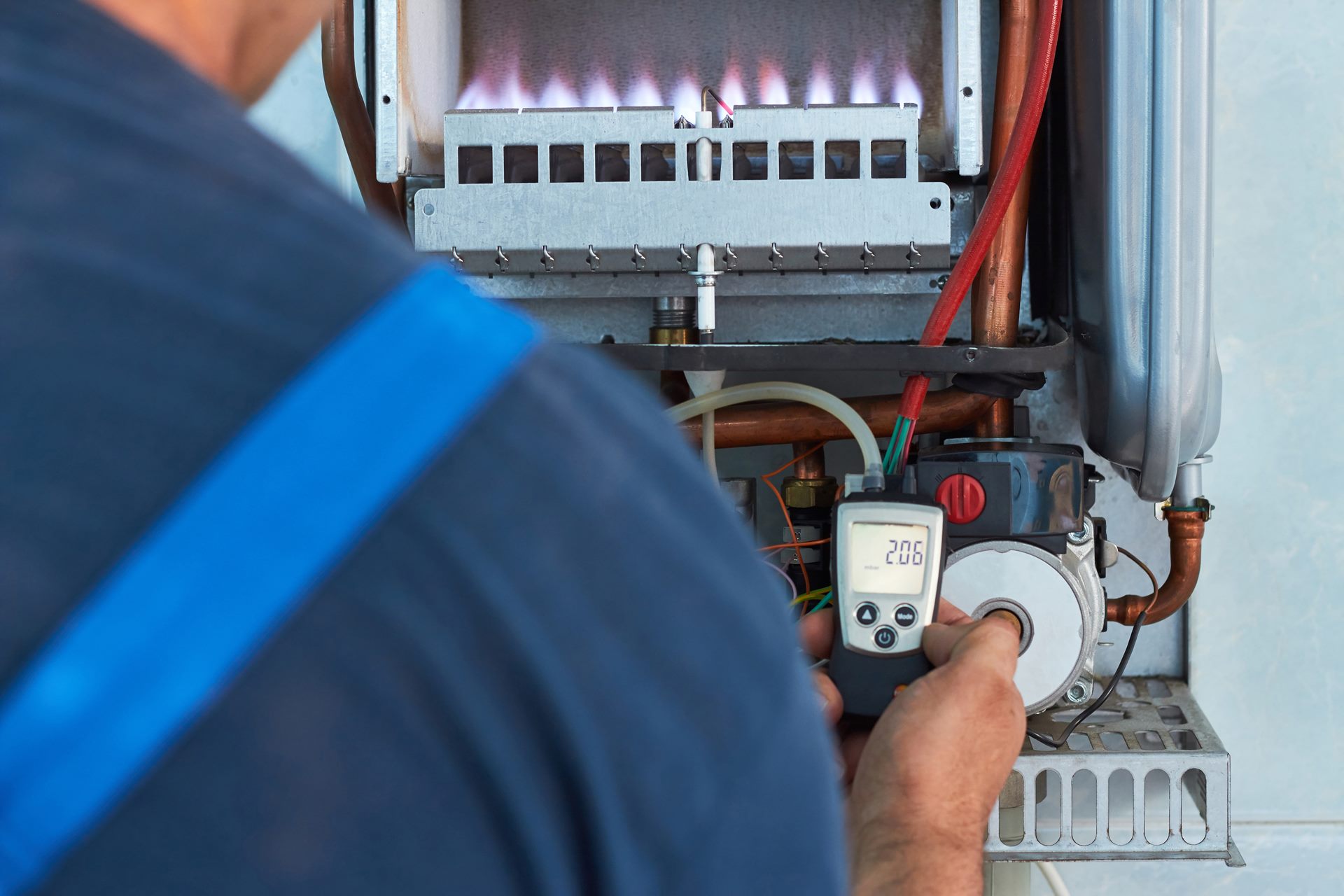 A man uses a digital thermometer to monitor the temperature of a gas boiler