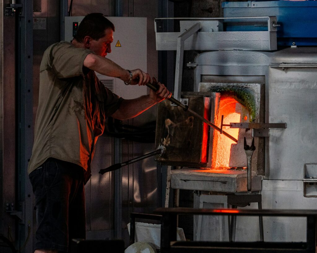 A man carefully monitors the glass furnace, ensuring optimal temperature for glass production