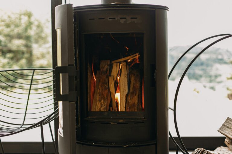 A cozy room featuring a wood burning stove beside a comfortable chair