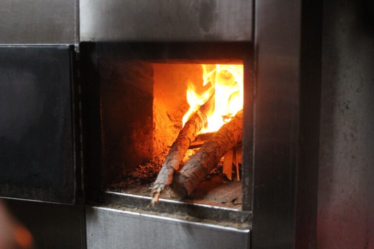 A fire burns brightly inside a metal oven, showcasing the intense heat