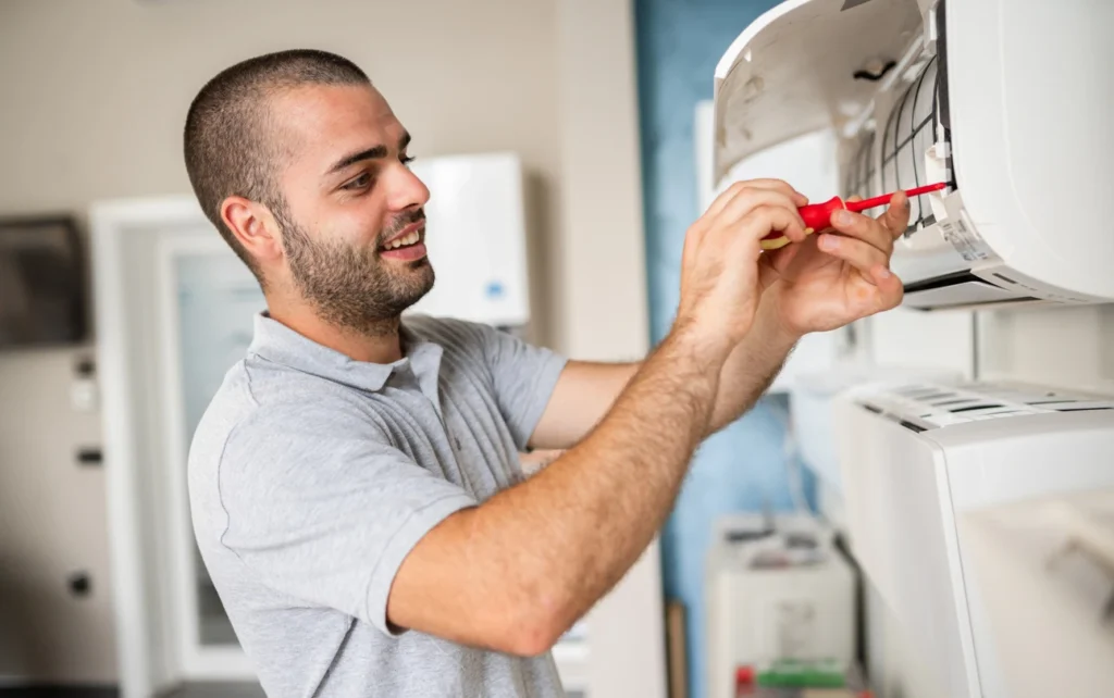 A man diligently works on an air conditioning unit