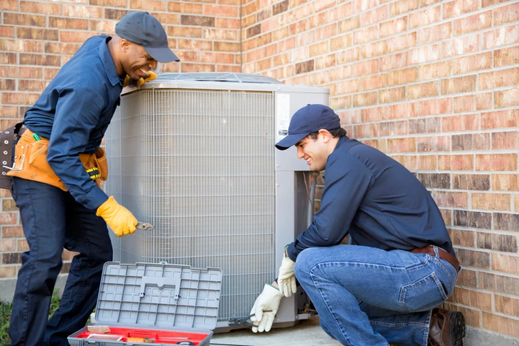 Two technicians working together on an air conditioning unit