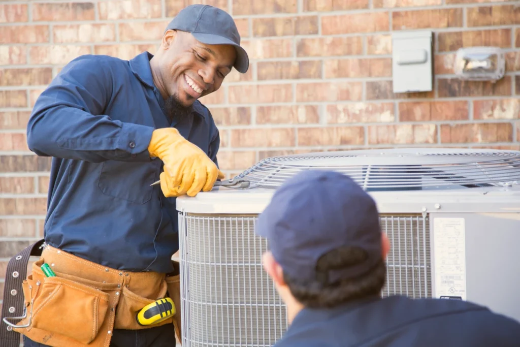 Two technicians working together on an air conditioning unit