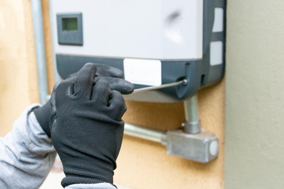 A technician in gloves is servicing a water heater